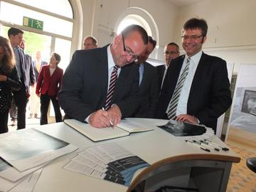 Innenminister Pistorius trägt sich das Gästebuch des Museums Friedland ein