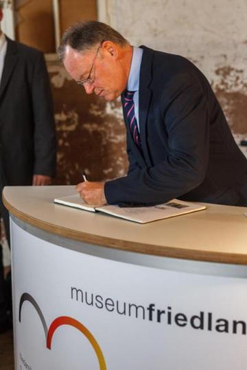Ministperpräsident Stephan Weil trägt sich in das Gästebuch des Museums Friedland ein, dankt für den freundlichen Empfang und wünscht viel Erfolg auf dem Weg zum Museum Friedland