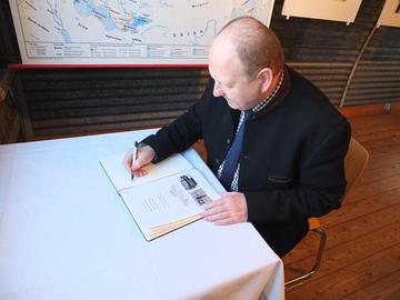 MdB Klaus Brähmig trägt sich in das Gästebuch des Museums Friedland ein.